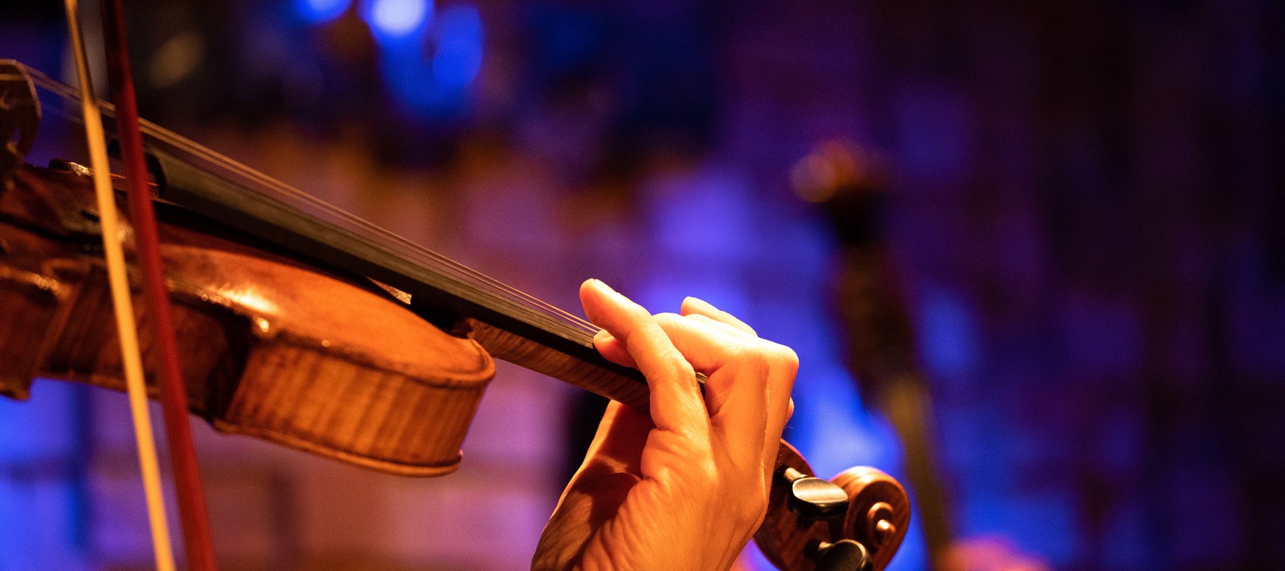 Hands play string instruments in an orchestra.